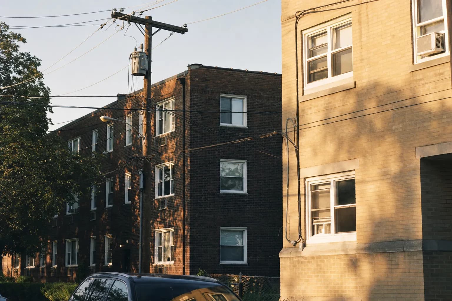 Utility power lines and a pole transformer behind a row of apartment buildings