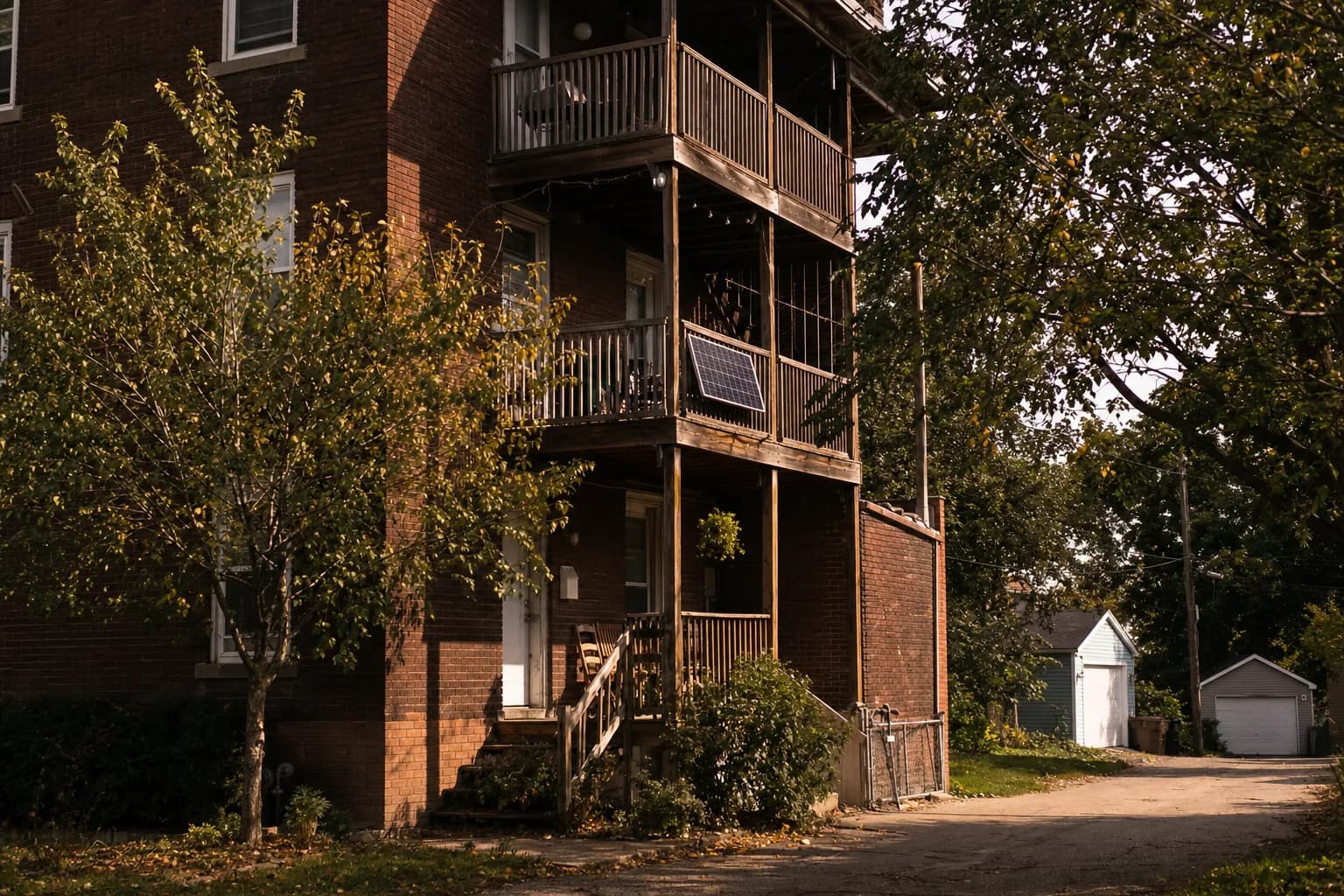 A solar panel on the rear porch railing of a red-brick three-flat