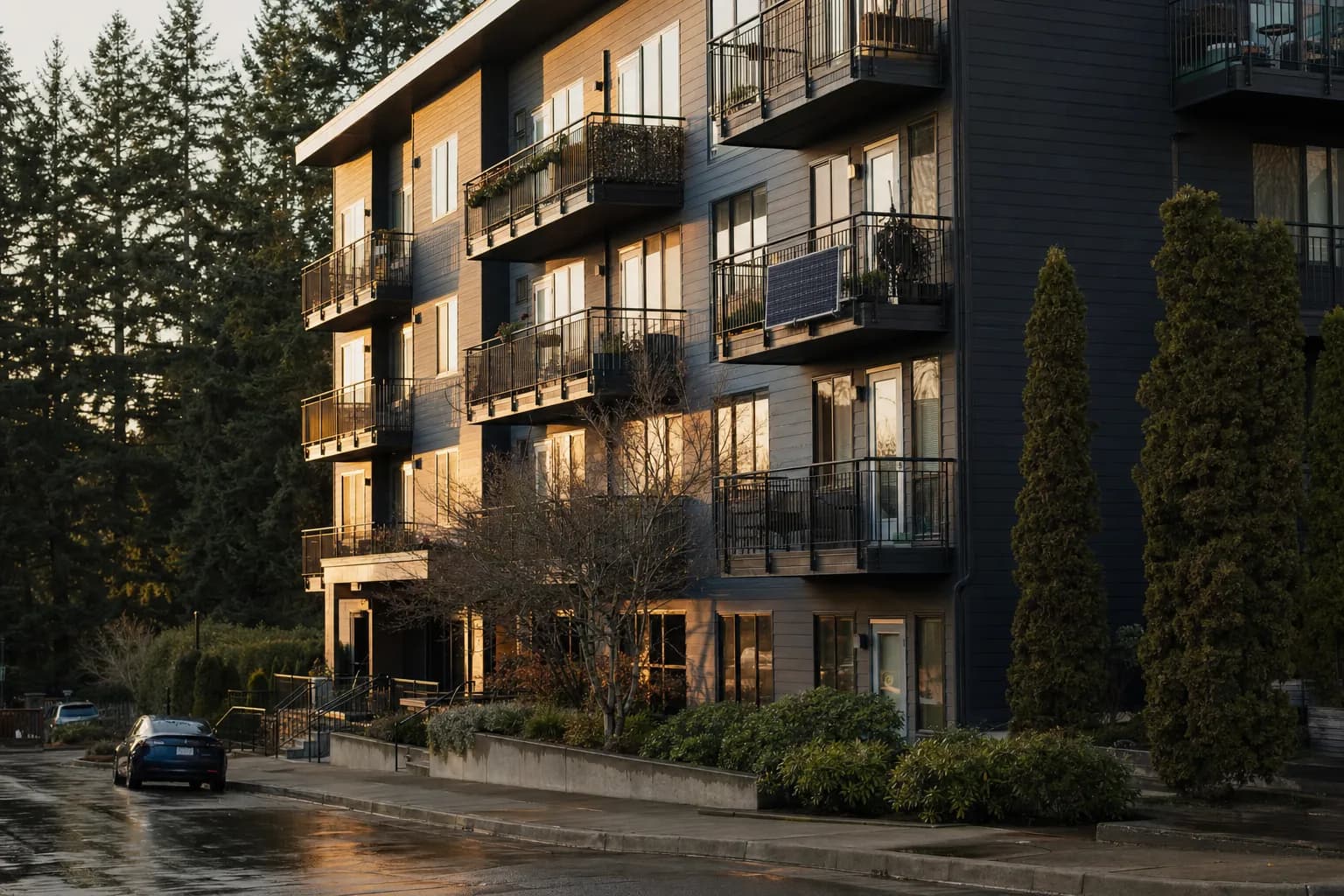 A solar panel on a steel balcony railing of a modern apartment building among evergreens